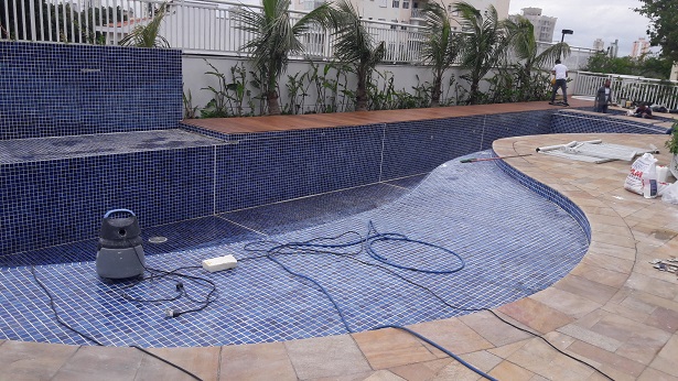 Profissional aplicando rejunte em piscina
